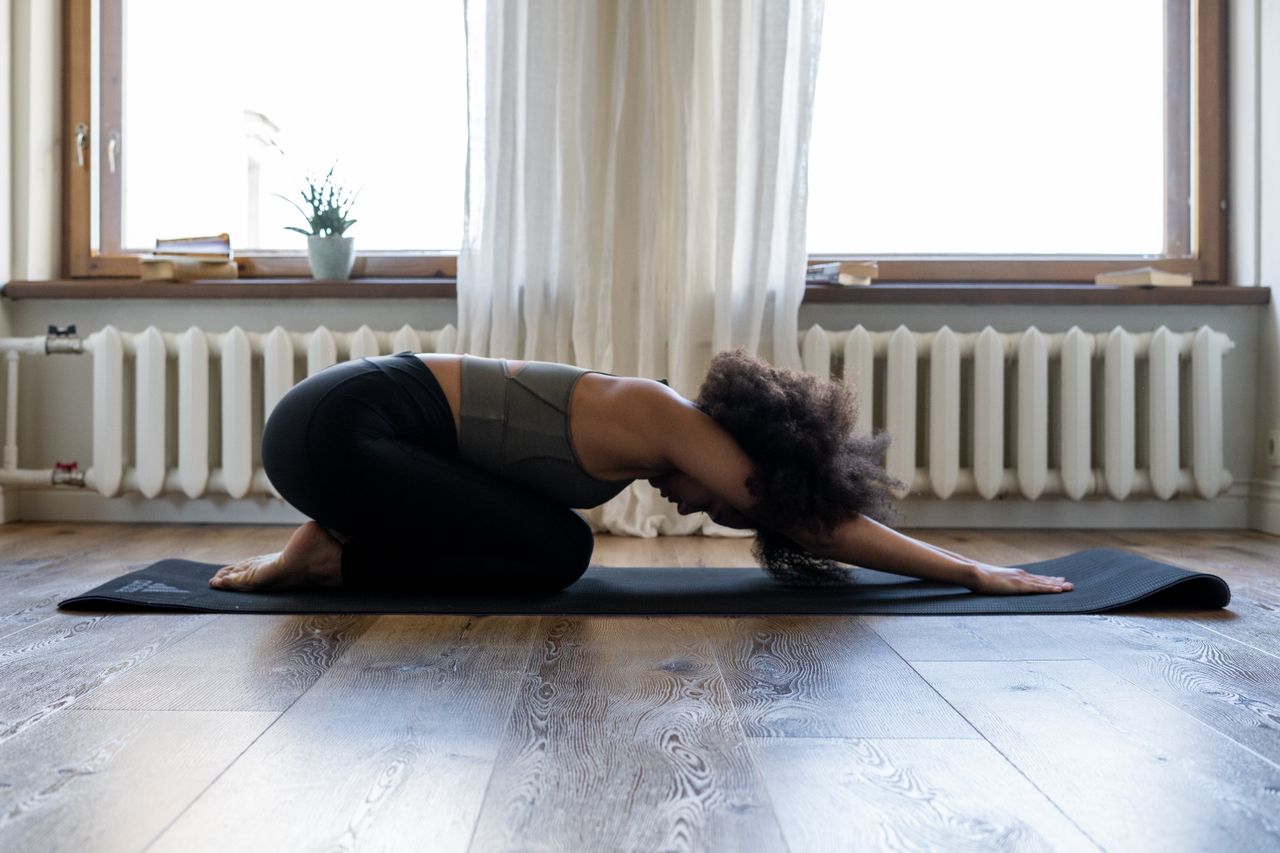 Offerings Woman practicing yoga at home on a mat in a cozy room. Embracing fitness and wellness indoors.