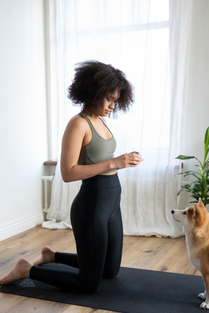 gallery-01 A woman practicing yoga with her dog at home, creating a peaceful and cozy atmosphere.