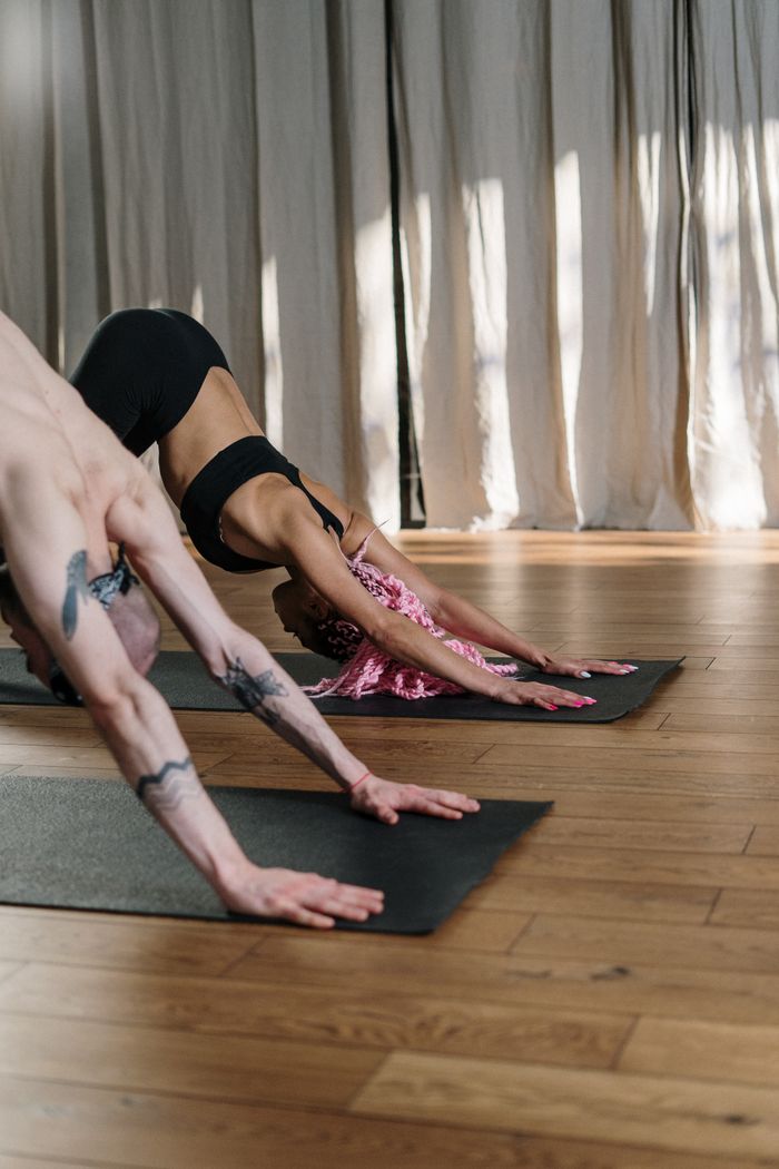 Offerings Two people practicing yoga indoors showcasing flexibility and fitness.